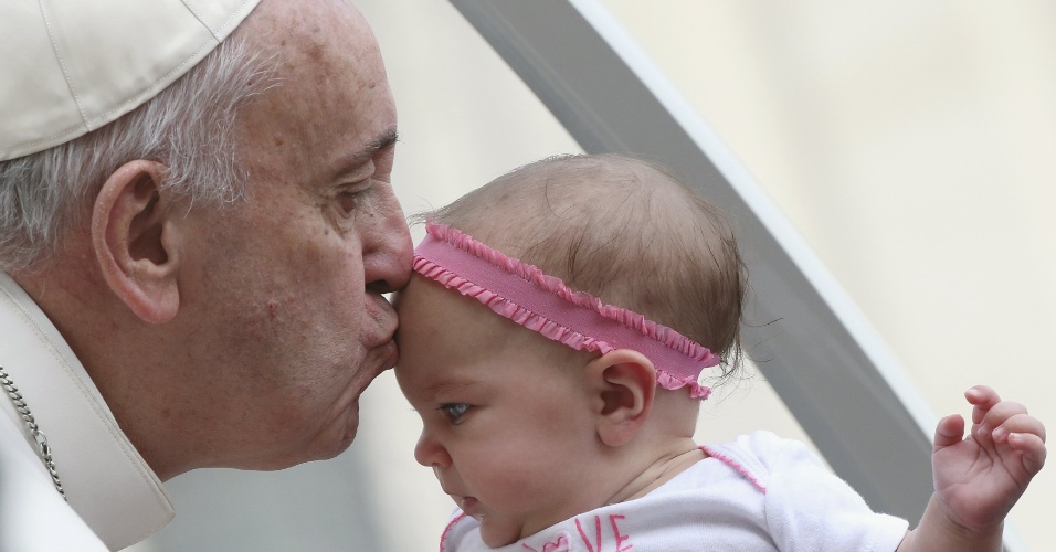 14.out.2015 - Papa Francisco beija bebê na chegada à audiência semanal na Praça de São Pedro, no Vaticano