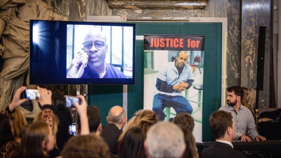 12.nov.24 - O pianista de jazz espanhol Albert Marques olha para um vídeo do americano Keith LaMar tocando da Penitenciária Estadual de Ohio, nos EUA, onde ele é condenado à morte, durante um concerto no Old Bailey Grand Hall, em Londres