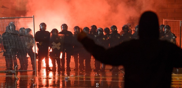 Manifestante gesticula em frente à policiais, durante confrontos próximos à sede do Parlamento da Suíça