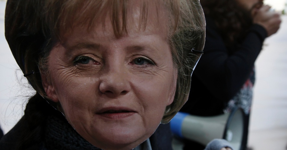 18.mar.13 - Manifestante com máscara de Angela Merkel protesta em frente ao Parlamento do Chipre, em Nicósia. O governo negociava um plano de resgate internacional, cuja contrapartida seria confiscar parte dos depósitos bancários do país