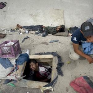 Abimael Martínez, 37, olha para fora do buraco onde vive perto do rio Tijuana, no noroeste do México - David Mung/EFE