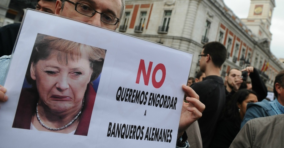 19.mai.11 - Homem segura cartaz com a foto da chanceler alemã, Angela Merkel, e a frase ?Não queremos engordar os banqueiros alemães?, em protesto em Madri, na Espanha