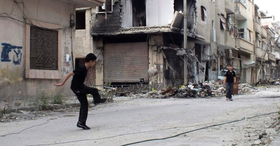 30.mai.2013 - Crianças jogam futebol em uma rua destruída na área sitiada de Homs, na Síria, na quarta-feira (29)