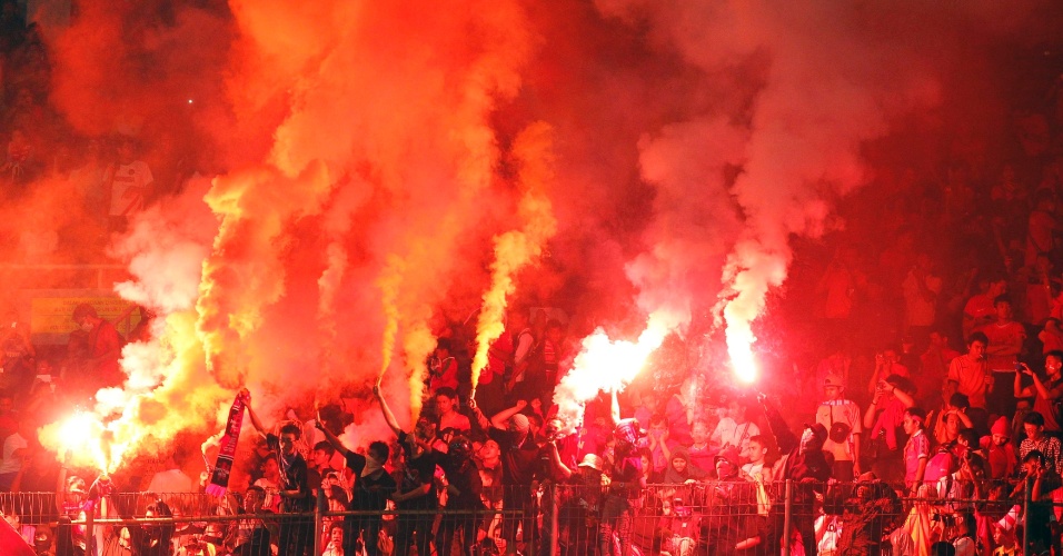 7.jun.2013 - Torcedores da seleção da Indonésia acendem fogos de artifício durante jogo de futebol contra a Noruega, em Jacarta, na Indonésia