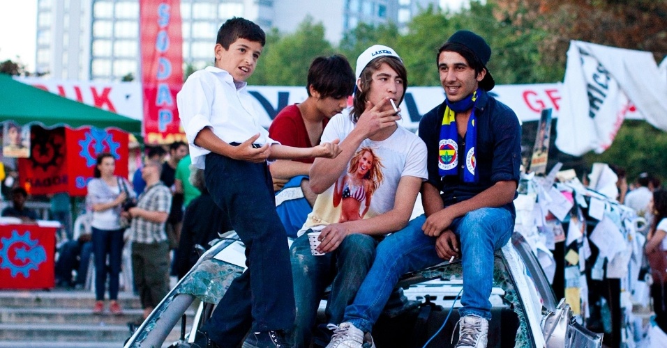 10.jun.2013 - Jovens turcos sentam em cima de carro de polícia destruído na praça Taksim, em Istambul, epicentro das manifestações contra o premiê Recep Tayyip Erdogan