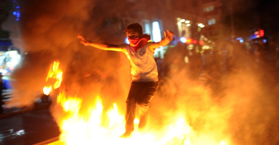 10.jun.2013 - Menino pula fogueira em meio a protesto no bairro de Gazi, em Istambul.