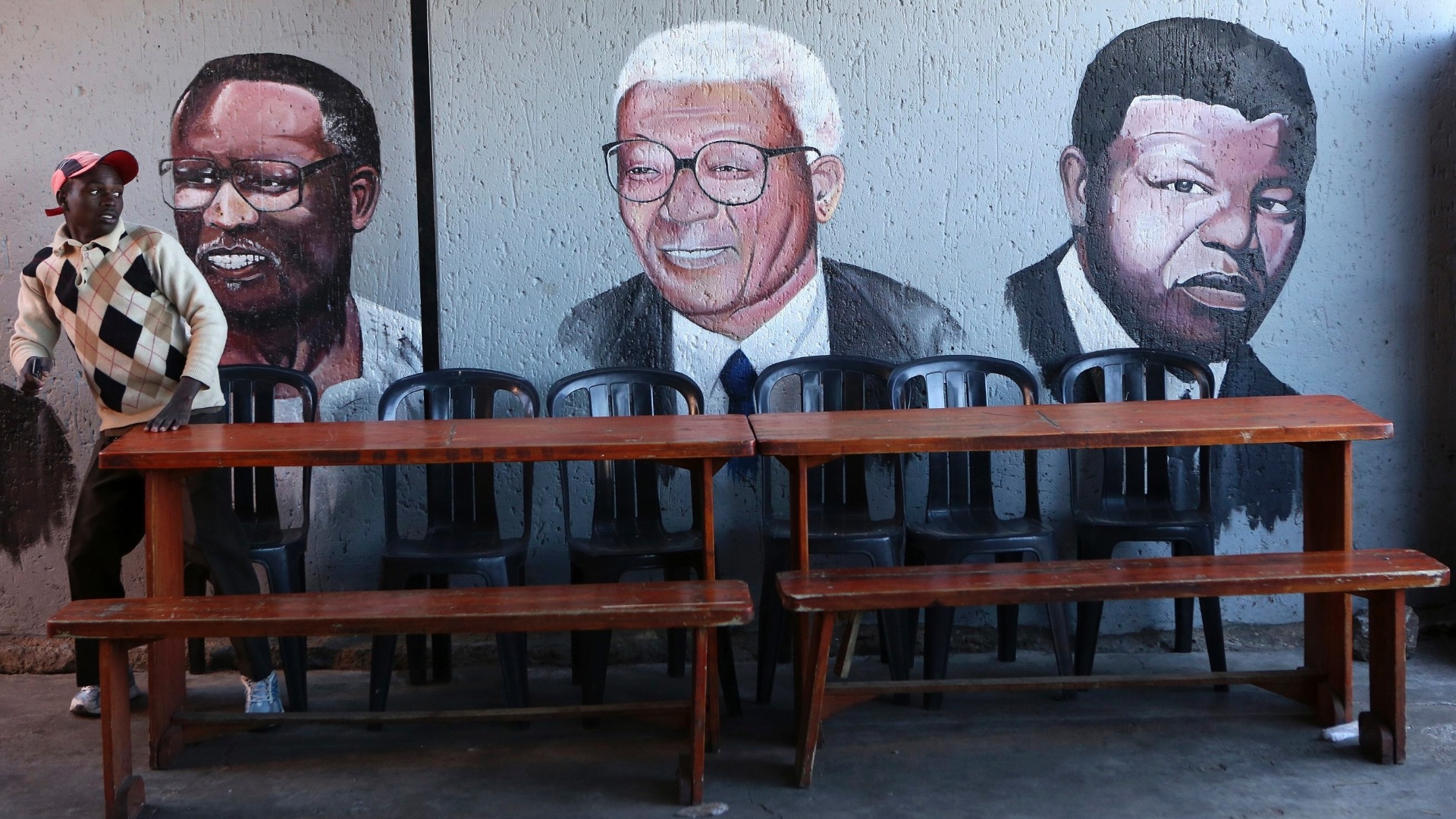 9.jun.2013 - Homem senta-se próximo a uma parede pintada com retratos do presidente da CNA (Congresso Nacional Africano), Oliver Tambo (esquerda), o ativista anti-aparatheid sul africano, Walter Sisulu, e líder da CNA e ex-presidente da África do Sul, Nelson Mandela, em Soweto, neste domingo (9). Mandela permanece no hospital pelo terceiro dia seguido nesta segunda-feira (10) com uma infecção pulmonar, e seu estado de saúde continua "grave, mas estável", inalterado desde sábado (8), informou o governo - Siphiwe Sibeko/Reuters