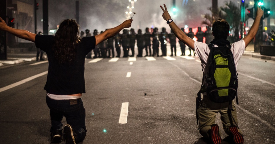 11.jun.2013 - Manifestantes se ajoelham diante de PMs durante protesto na avenida Paulista, em São Paulo. O homem da direita foi atingido por uma bala de borracha na sequência. O da esquerda, mais tarde, detido