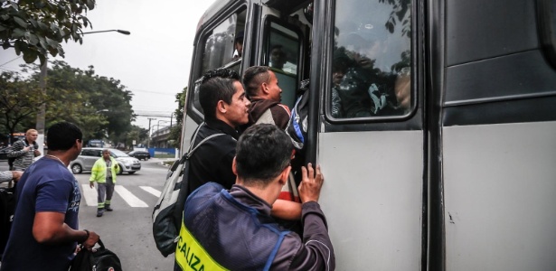 Pessoas se penduram em ônibus lotado em Santo Amaro, zona sul de São Paulo - Leandro Moraes/UOL