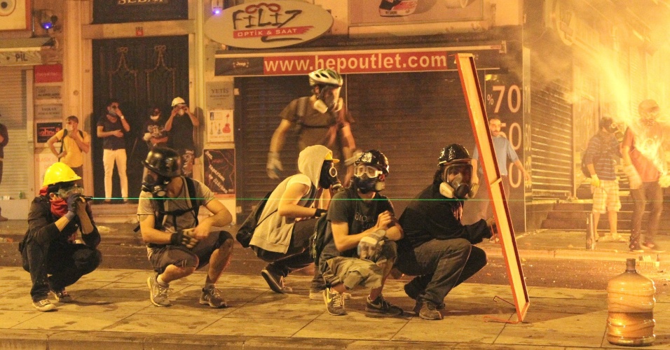 16.jun.2013 - Manifestantes usam um objeto para se proteger durante confrontos com a polícia em área próxima à praça Taksim, em Istambul, Turquia. Milhares de manifestantes, em diferentes cidades da Turquia, realizaram atos em resposta à ação da polícia que desalojou à força, neste sábado (15), os últimos manifestantes que ocupavam o parque Gezi, em Istambul. O local é o epicentro dos protestos contra o governo, que agitam a Turquia há duas semanas