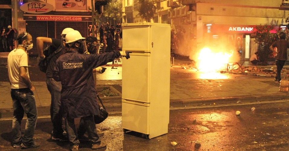16.jun.2013 - Manifestantes usam uma geladeira como escudo para se proteger durante confrontos com a polícia em área próxima à praça Taksim, em Istambul, Turquia. Milhares de manifestantes, em diferentes cidades da Turquia, realizaram atos em resposta à ação da polícia que desalojou à força, neste sábado (15), os últimos manifestantes que ocupavam o parque Gezi, em Istambul. O local é o epicentro dos protestos contra o governo, que agitam a Turquia há duas semanas