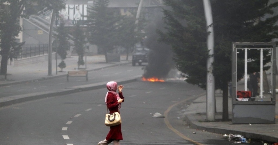 16.jun.2013 - Mulher cruza avenida perto de local onde há confrontos entre manifestantes e policiais durante protestos em Ancara, na Turquia, neste domingo (16)