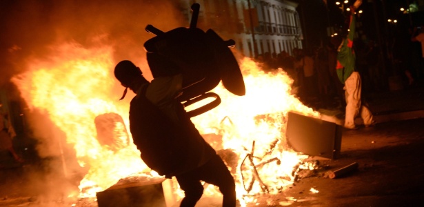 Manifestante atira cadeira em fogueira feita em rua durante protestos no centro do Rio de Janeiro - Lluis Gene/AFP 