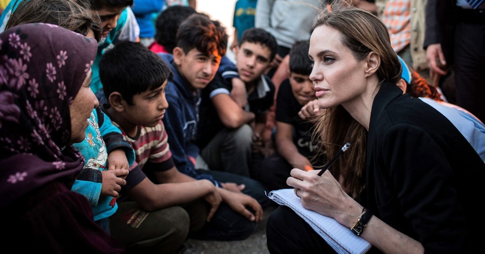 19.jun.2013 - Angelina Jolie conversa com crianças sírias que vivem em um campo de refugiados na fronteira da Jordânia. A viagem da atriz, que é embaixadora da ONU (Organização das Nações Unidas), coincide com o Dia Mundial do Refugiado, celebrado nesta quinta-feira (20)