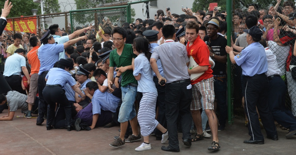 20.jun.2013 - Pessoas caem durante empurra-empurra nesta quinta-feira (20) enquanto tentam ver David Beckam, durante uma visita do ex-jogador de futebol à Universidade de Tonji, em Xangai (China). Ao menos cinco pessoas se feriram, incluindo uma policial, de acordo com a imprensa local e um fotógrafo da AFP que presenciou a cena
