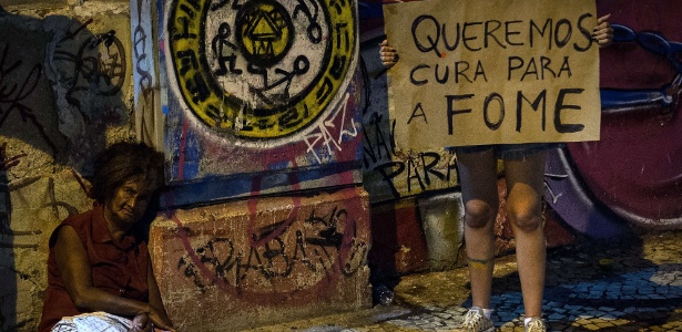 Manifestante segura cartaz perto de sem-teto no centro de Recife (PE) - Yasuyoshi Chiba/AFP