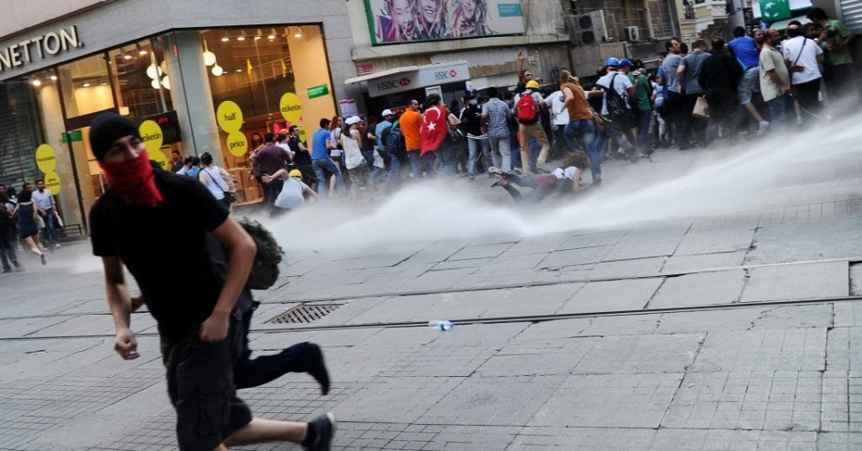13.jul.2013 - Polícia turca usa jato d'água para dispersar manifestantes em rua comercial de Istambul, neste sábado (13). O confronto começou quando centenas de manifestantes tentaram entrar na praça Taksim e no oarque Gezi, berço da onda de protestos contra o governo que agitou a Turquia em junho