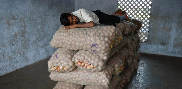 Comerciante dorme em sacos de cebolas em um mercado na cidade de Ahmedabad, na Índia - Amit Dave/Reuters