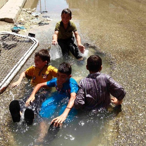 Crianças brincam em poça formada em cratera de rua em Aleppo, na Síria - 23.jul.2013 - Hamid Khatib/Reuters