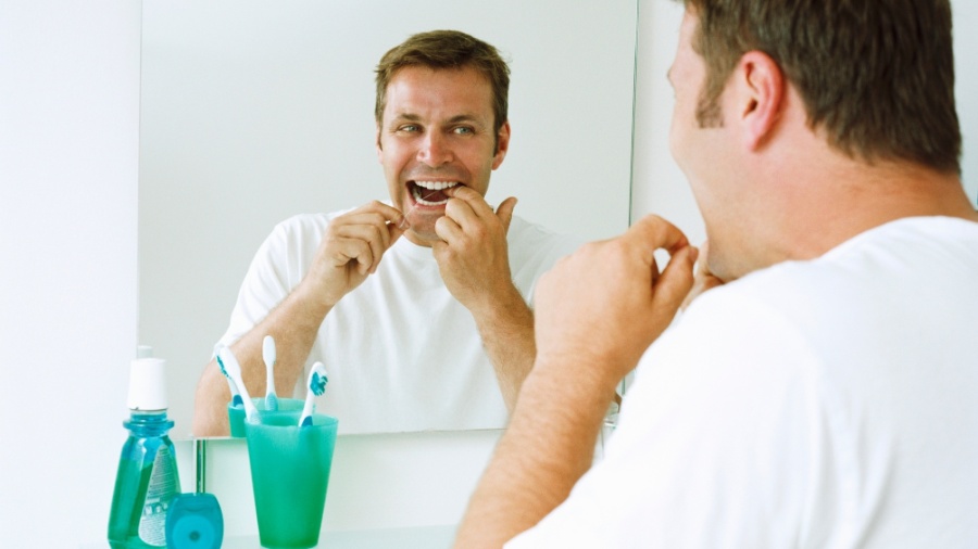 homem passa fio dental no banheiro, saúde bucal, escolva de dente, enxaguador - Thinkstock