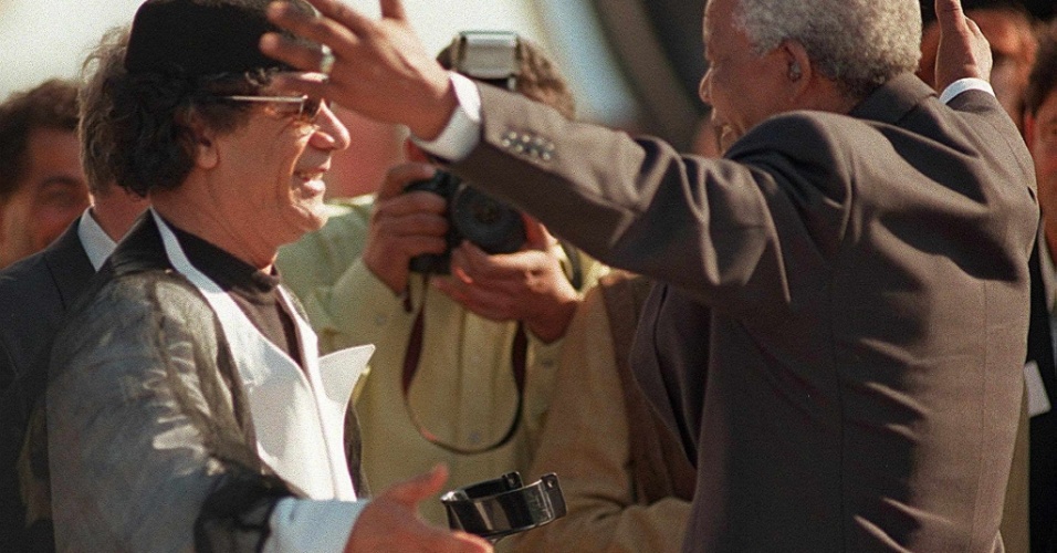 1999 - O já ex-presidente da África do Sul, Nelson Mandela, se prepara para abraçar seu colega da Líbia, Muammar Gaddafi, na chegada deste à Cidade do Cabo