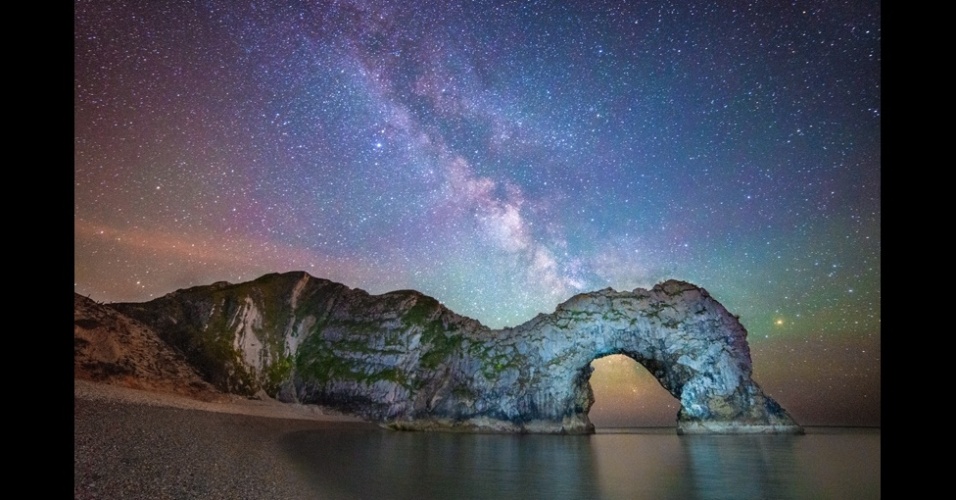 31.jul.2013 - A foto acima mostra Durdle Door, a formação em uma praia de Dorset, na Inglaterra, e a Via Láctea. A imagem foi selecionada entre os finalistas na categoria revelação