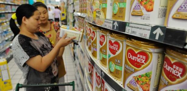 Consumidora chinesa é auxiliada por funcionária de supermercado a escolher produto com derivados de leite da Danone, após escândalo de empresa da Nova Zelândia - Stringer /Reuters