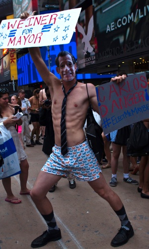5.ago.2013 - Homem dança vestido com máscara do candidato à prefeitura de Nova York, Anthony Weiner, e cartaz em seu apoio, durante evento em Nova York buscando quebrar o recorde de maior número de pessoas em roupas íntimas reunidas no mesmo local. Os organizadores esperam superar a marca de 2.270 pessoas em Times Square, no centro de Nova York