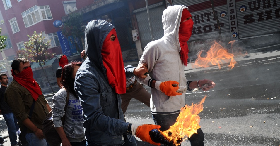 9.set.2013 - Manifestantes mascarados e simpatizantes do partido de esquerda seguram coquetel molotov aceso durante protestos na Turquia, nesta segunda-feira (9), no distrito de Okmeydani, em Instambul