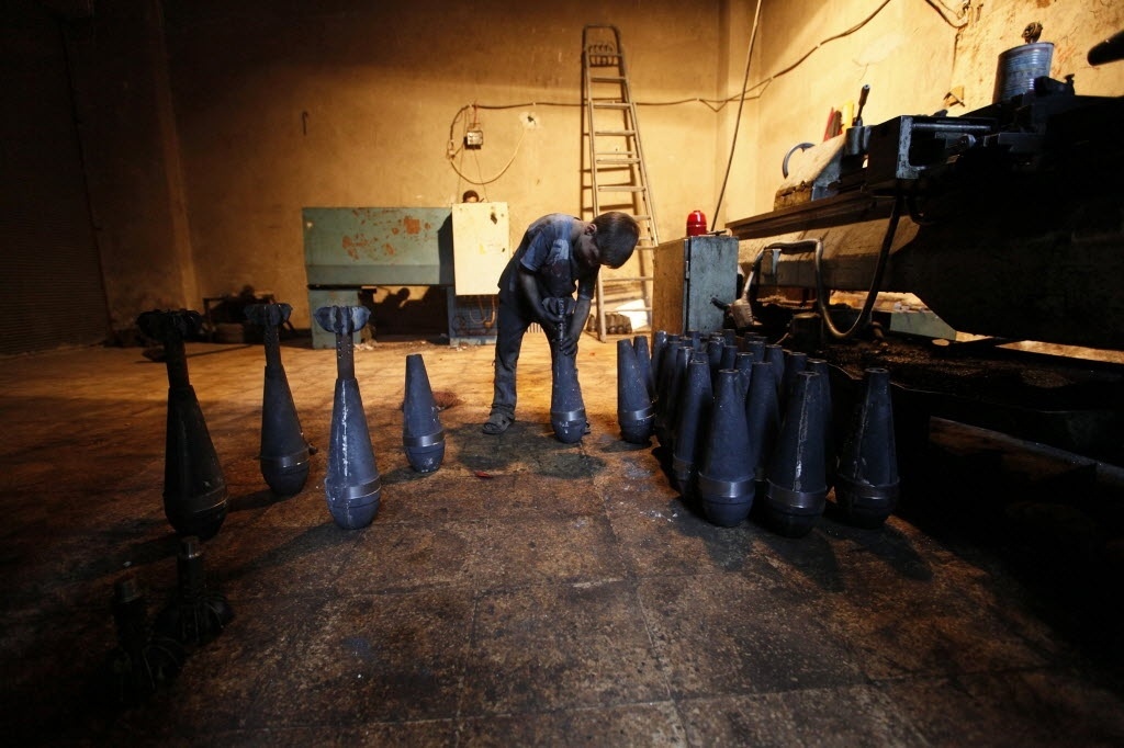 7.set.2013 - Issa, 10, manuseia morteiros durante dia de trabalho em uma fábrica de armas do Exército Livre da Síria em Aleppo, reduto da revolta contra o presidente sírio Bashar Assad. Ele trabalha com o pai na fábrica por dez horas todos os dias, exceto às sextas-feiras - Hamid Khatib/Reuters