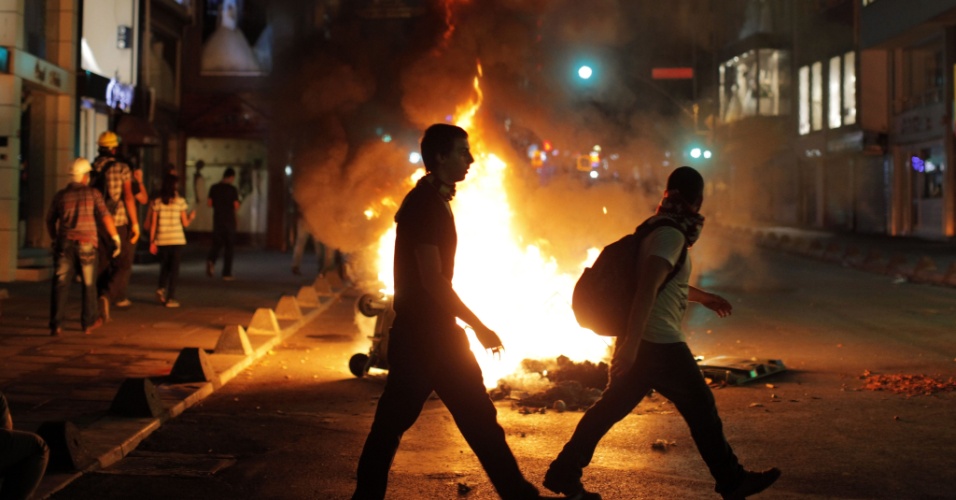 12.set.2013 - Manifestantes passam em frente a uma barricada em rua de Kadikoy, em Istambul (Turquia), nesta quinta-feira, durante protesto contra a repressão policial que resultou na morte de jovem de 22 anos no sul da Turquia, durante confronto com policiais