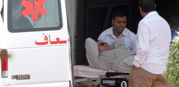 Deitado em uma maca, Hosni Mubarak é colocado por médicos em uma ambulância para que seja levado de helicóptero do hospital militar Maadi para a Academia de Polícia no Cairo, capital do Egito, onde ocorre nova audiência de seu julgamento neste sábado (14) - Khaled Elfiqi/EPA/Efe