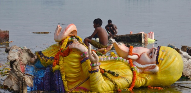 Garoto indiano senta em estátua de divindade Ganesh mergulhada no lago Hussain - Krishnendu Halder/Reuters