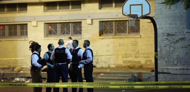 Detetives da polícia de Chicago, nos Estados Unidos, se reúnem em quadra de basquete enquanto investigam cena de crime onde ao menos 13 pessoas, incluindo uma criança de três anos, ficaram feridas em um tiroteio em um parque na zona sul da cidade, em setembro. Nenhuma pessoa foi detida por conexão com o tiroteio - Scott Olson/Getty Images/AFP