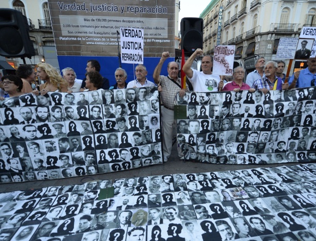 Manifestantes seguram faixas com retratos de pessoas mortas ou torturadas durante a ditadura de Francisco Franco em frente à antiga sede da Segurança Nacional, em Madri - Gerard Julien/AFP