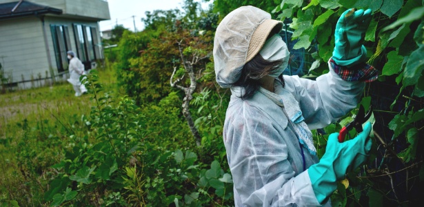 Mulher poda plantas em sua casa em Namie, no Japão, cidade que foi completamente evacuada após o desastre nuclear na usina de Fukushima - Tomas Munita/The New York Times