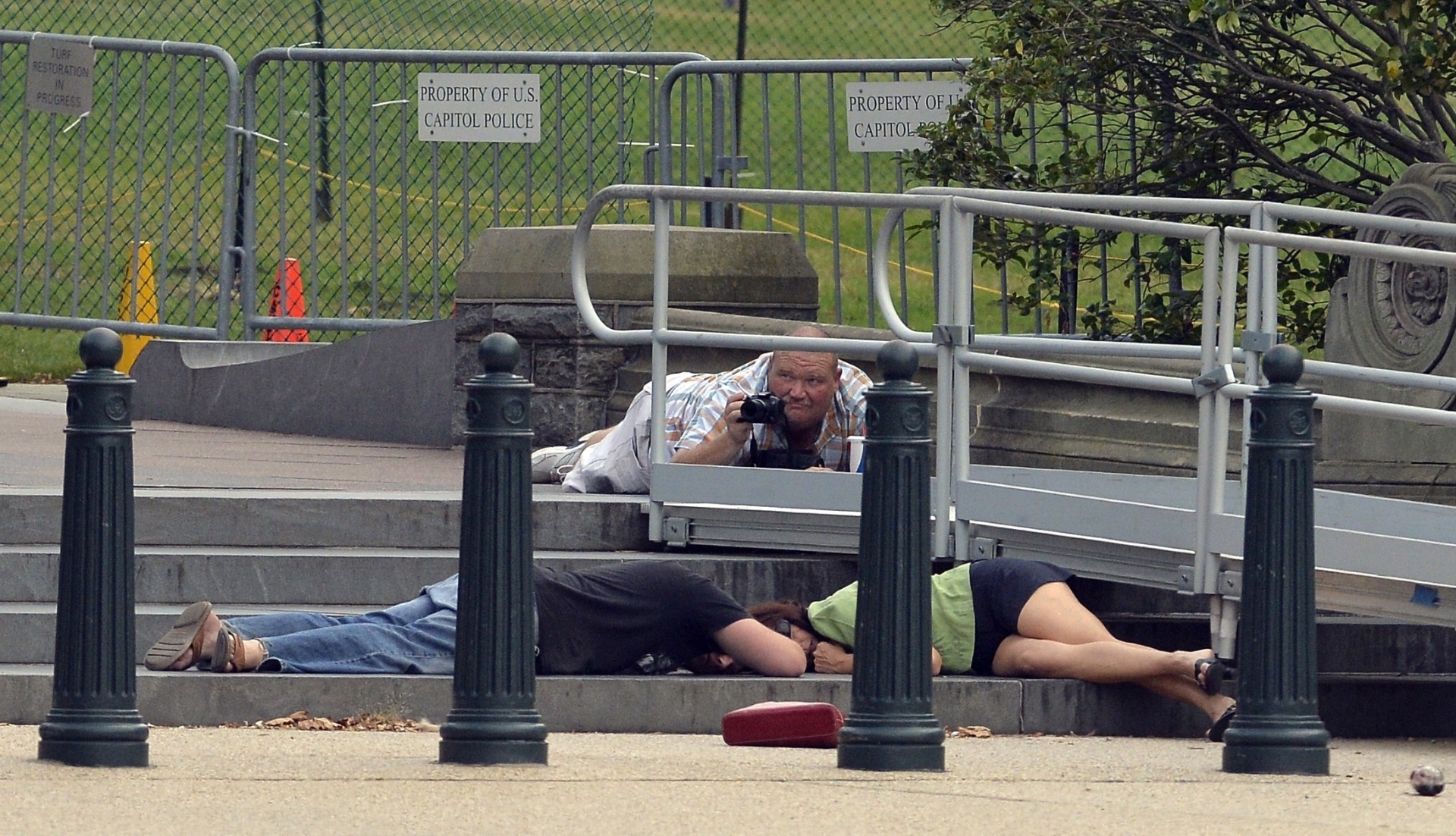 3.out.2013 - Pessoas se deitam no chão tentando se proteger de disparos de arma de fogo nesta quinta-feira (3), nos arredores do Capitólio, em Washington. O local foi colocado em bloqueio de segurança, após tiros terem sido ouvidos do lado de fora do prédio onde funciona o Congresso norte-americano - Jewel Samad/AFP