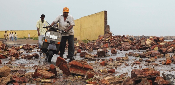 Indianos caminham sobre escombros causados pelo ciclone "Phailin" neste sábado (12) - Reuters