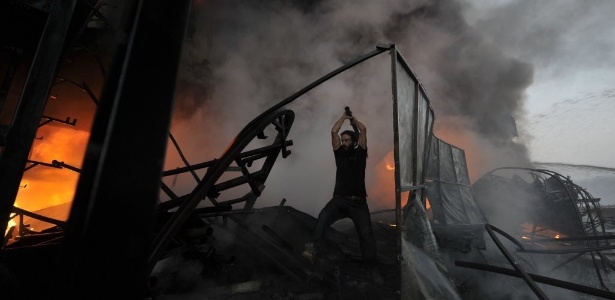 Homem trabalha para remover uma barreira e permitir o acesso do carro de bombeiros <br>em um incêndio em Benghazi, na Líbia. Imagem de 15 de outubro de 2013 - Esam Omran Al-Fetori/Reuters