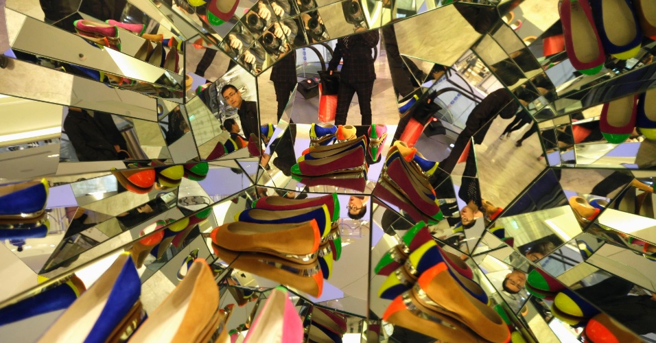 18.out.2013 - Um cliente olha para sapatos exibidos em uma vitrine espelhada na recém-inaugurada Galeries Lafayette, em Pequim, na China