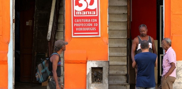 Homens conversam na porta de cinema particular em Havana, capital de Cuba. O governo de Raul Castro determinou neste sábado (2) o fechamento de todos os cinemas particulares da ilha, além de estipular um prazo para que lojas de revenda de roupas e produtos importados encerrem suas atividades
