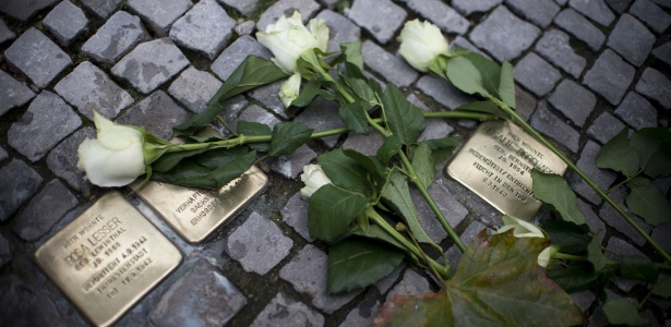 Flores são colocadas ao lado de placa com o nome de vítimas do nazismo, neste sábado (9), em Berlim