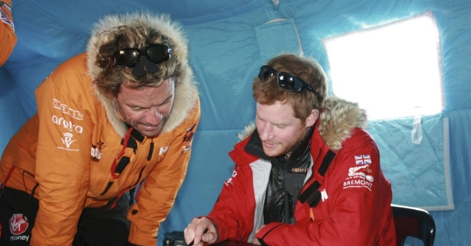 25.nov.2013 - O príncipe Harry e o ator Dominic West examinam documento durante expedição à Antártida. Os dois participam da expedição beneficente "Walking With The Wounded" (Caminhando com os feridos)