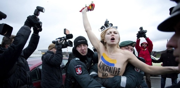 Policial da Lituânia segura uma ativista do movimento feminista Femen durante um protesto em Vilnius, capital do país, em 2013
