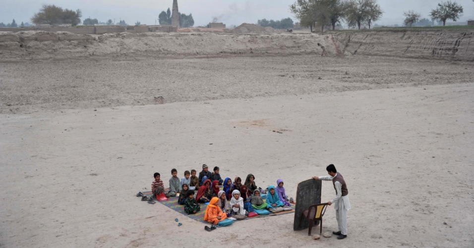 2.dez.2013 - Crianças afegãs recebem lições em uma sala de aula aberta em um campo de refugiados nos arredores de Jalalabad, na província de Nangarhar, nesse domingo (1º). A imagem foi divulgada hoje (2). Os afegãos têm vivido raros momentos de paz ao longo dos últimos 30 anos. Seu sistema educacional foi minado pela invasão soviética em 1979, a guerra civil nos anos 1990 e cinco anos de controle Talibã
