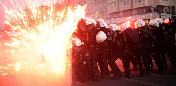Policiais turcos se protegem de fogos de artifício atirados por manifestantes curdos no centro de Istambul