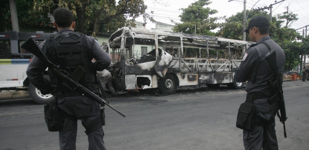 Policiais observam ônibus incendiado na favela Para Pedro, em Irajá - Fernando Souza/Agência O Dia/Estadão Conteúdo