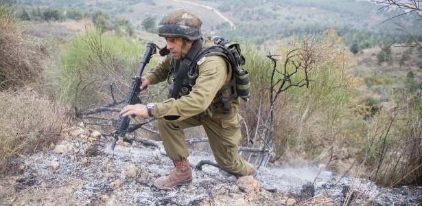 Soldado do exército de Israel procurar por restos de foguete disparados do Líbano neste domingo (29)