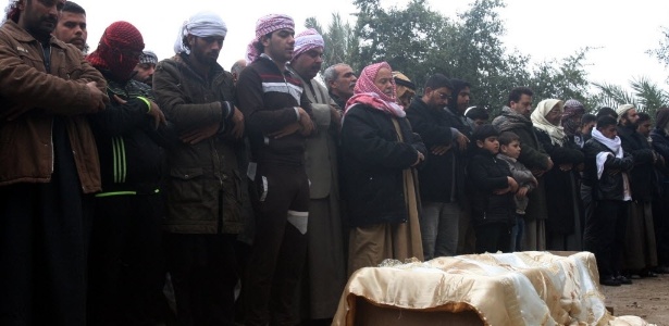 Amigos e parentes fazem orações ao redor do caixão de um homem morto em combate na cidade de Falluja - AFP