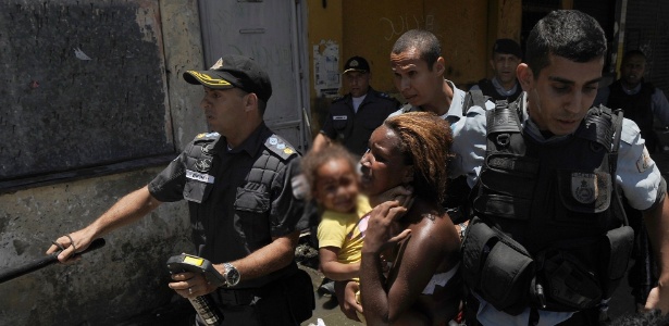 Policial puxa pelo pescoço uma mulher com uma criança no colo durante protesto dos moradores da favela do Metrô-Mangueira na terça - Fábio Teixeira/Parceiro/Agência O Globo